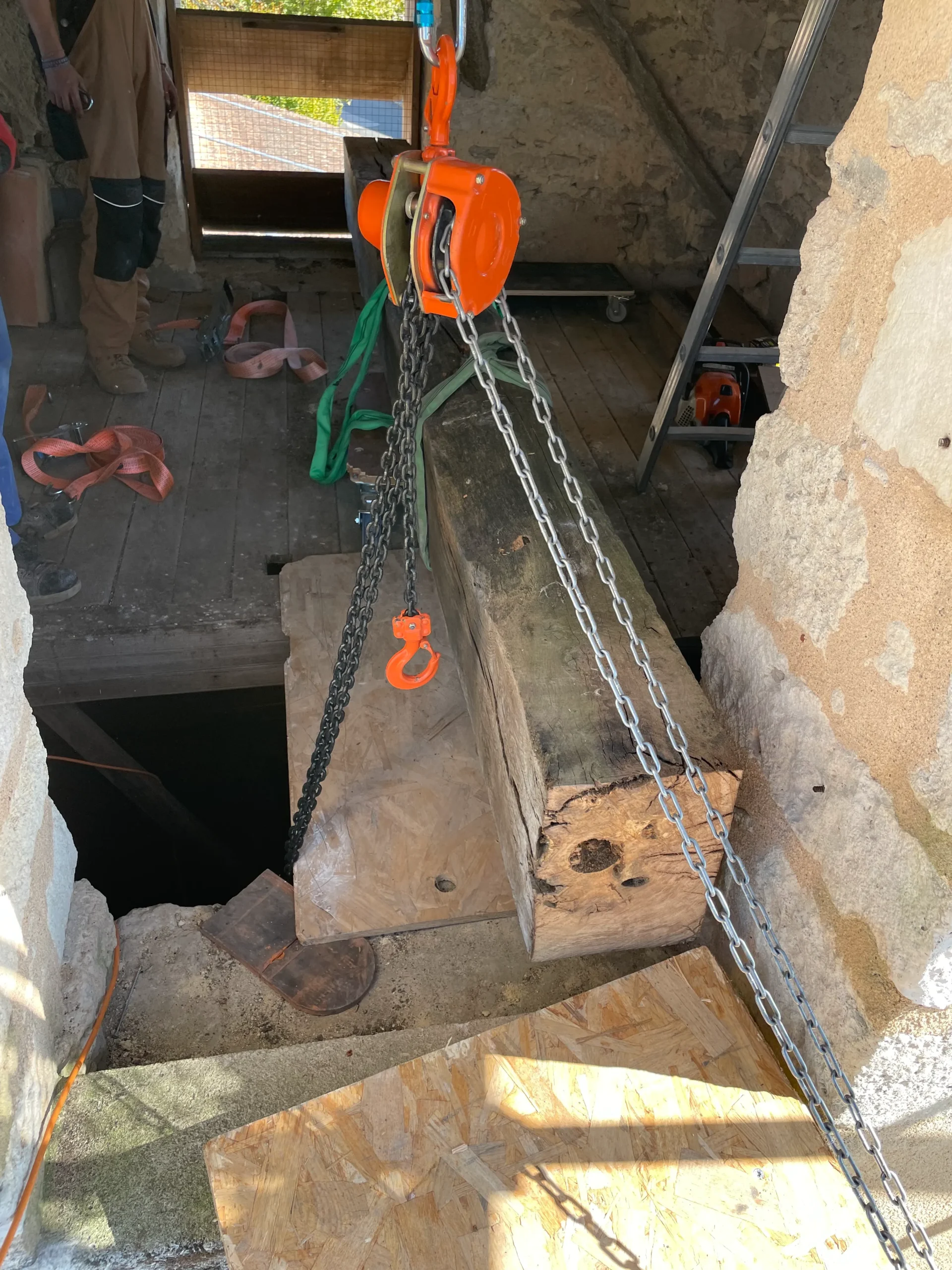 Manutention d’une poutre ancienne au palan dans le clocher de l’église