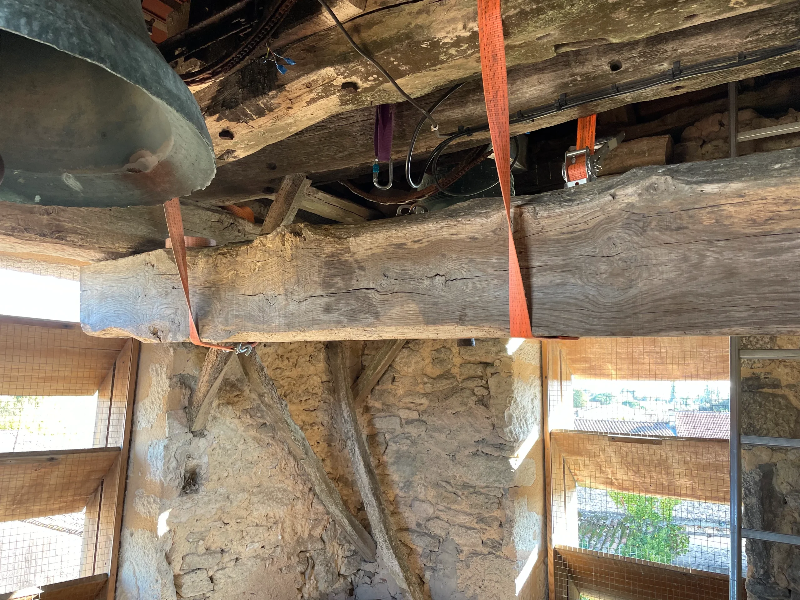 Poutre ancienne élinguée sous les cloches pendant les travaux de charpente