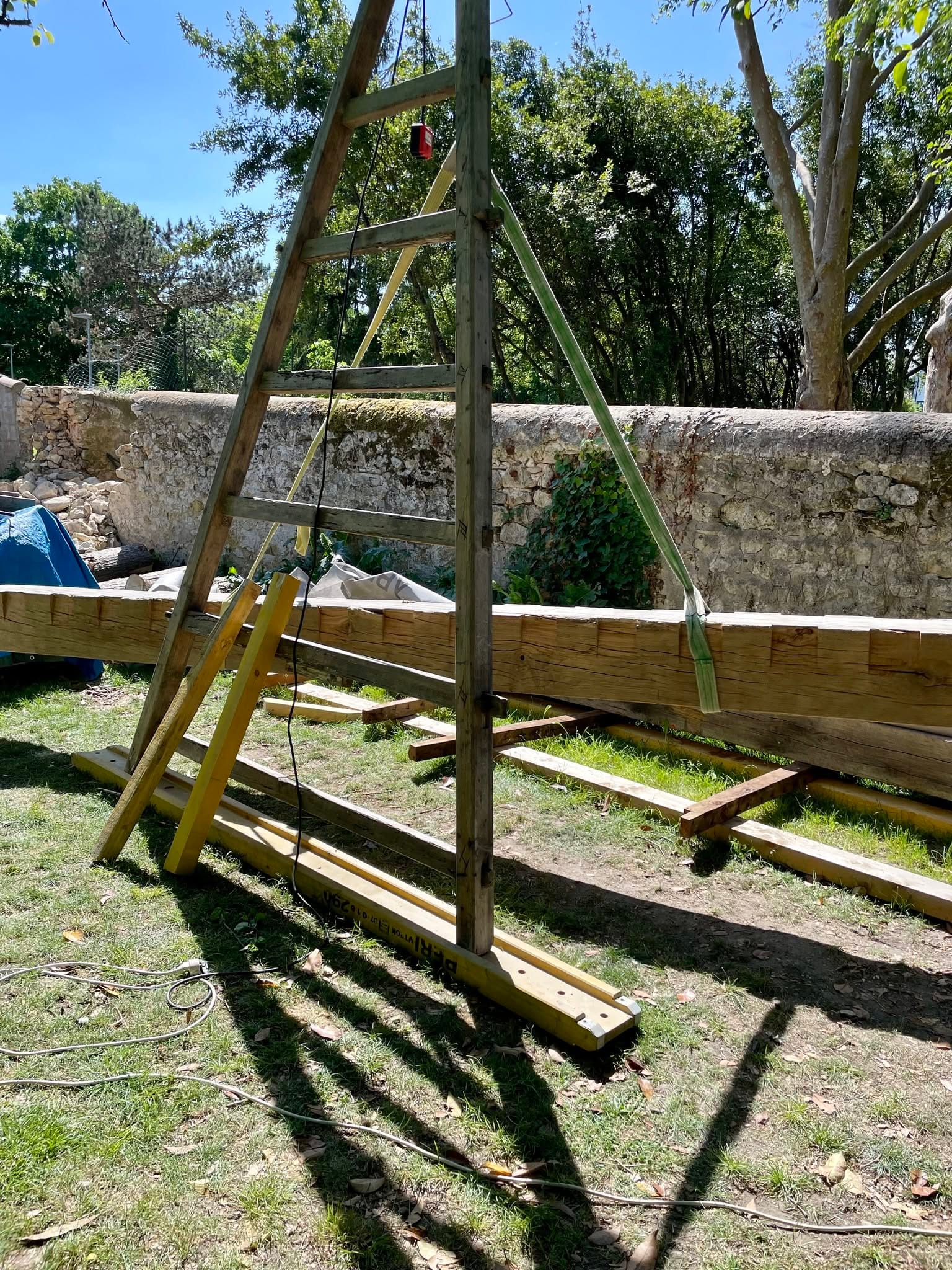 Manutention d’une poutre du plancher de Blaye avec une chèvre en bois et un palan en extérieur