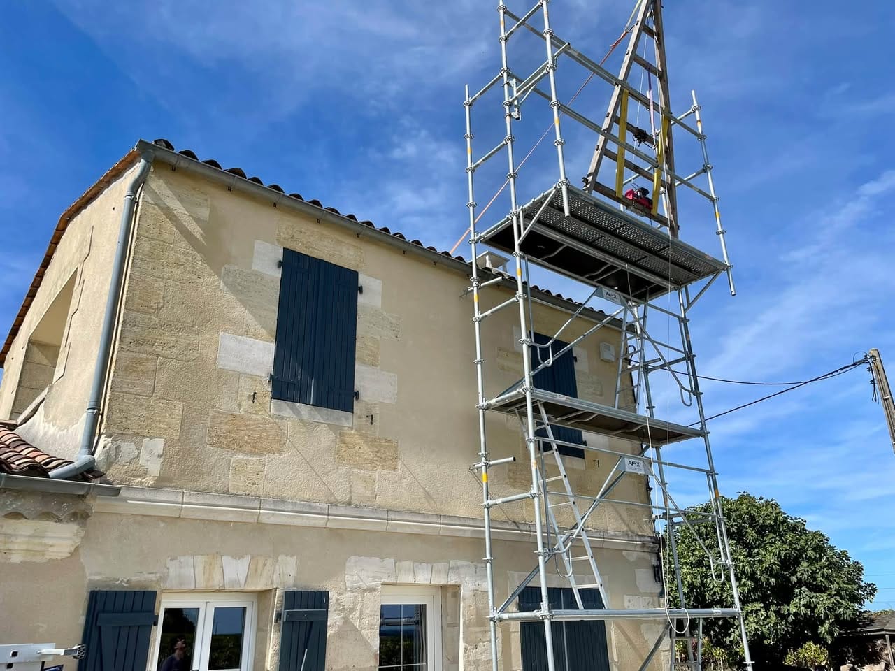 Chèvre en bois sur échafaudage à hauteur de toiture à Bourg